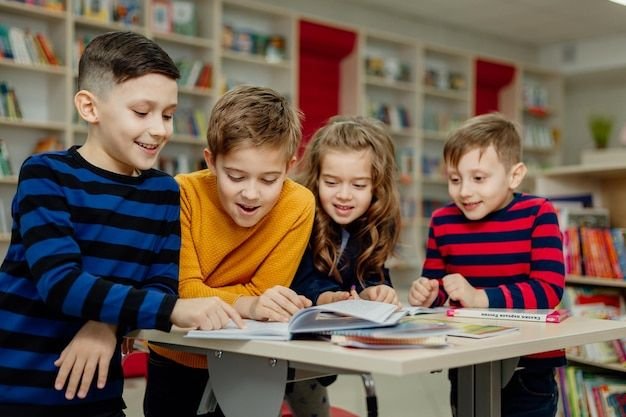 four children sitting at a table reading a book together